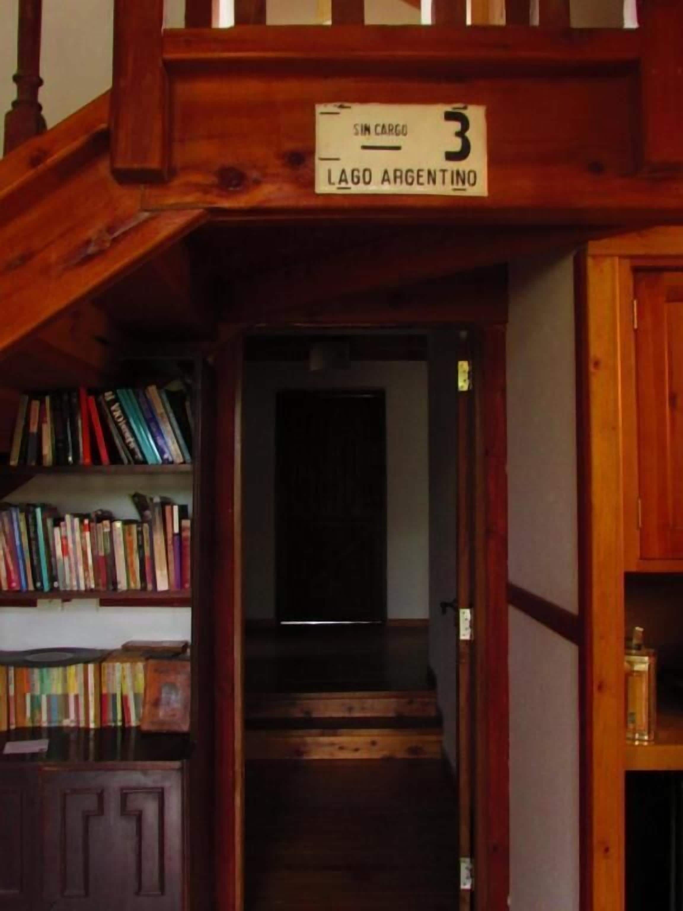 Uma escada de madeira leva a um quarto com a inscrição "SIN CARGO 3 LAGO ARGENTINO".