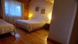 Ein gemütliches Zimmer mit zwei Betten, Holzböden und einer schrägen Decke.