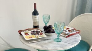 A dining table with a bottle of wine, a bowl of fruit, and a plate with a floral design.