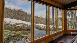 Quarto com amplas janelas com vista para uma paisagem coberta de neve e um teleférico.