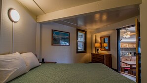 Quarto com cama, mesa de cabeceira, cômoda, espelho e janela.