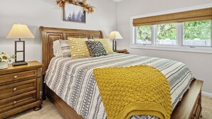 A bedroom with a wooden bed, two bedside tables, a window with a view, and a ceiling light. - Walk to Ski Lodge..Mountain Views..Includes Ski Lodge Locker (Sugar Mountain)