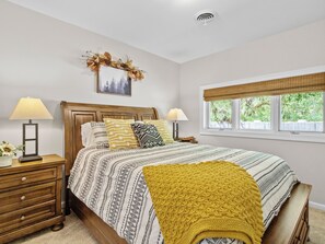 Una camera da letto con un letto di legno, due comodini, una finestra vista e una lampada a soffitto.
