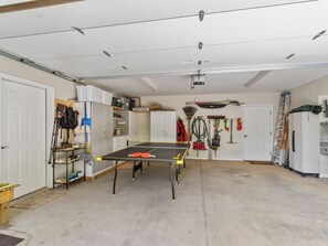 Un garage con un tavolo da ping pong, scaffali pieni di borse e diversi attrezzi.
