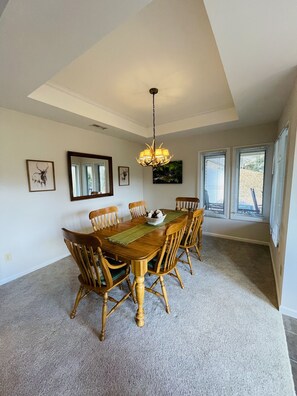 A dining room with a wooden table and chairs, a chandelier, and framed artwork on the walls. - Location! Walk to ski lodge! Includes owner's ski locker in ski lodge! (Sugar Mountain)