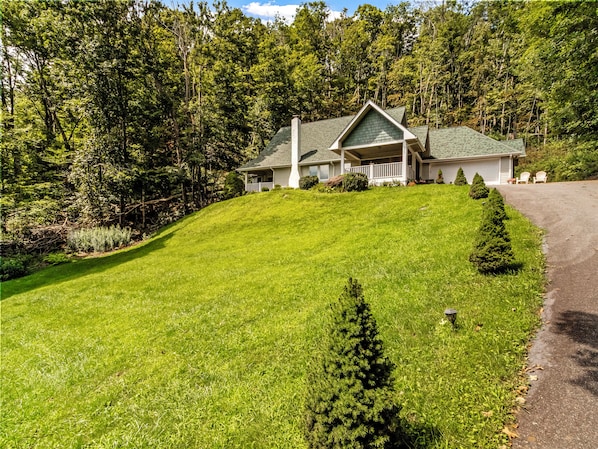A house with a sloped roof, a front porch, and a well-maintained lawn.