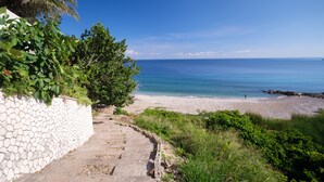 A stone pathway leading to a beach with a clear view of the ocean. - Luxurious 7-bedroom villa with spectacular sea view and private pool (Tower Isle)