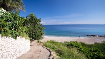 Un sentier de pierres qui mène à une plage d’où l’on a une vue dégagée sur l’océan.