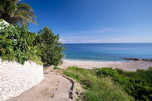 Un sentiero in pietra conduce a una spiaggia con vista libera sull'oceano.