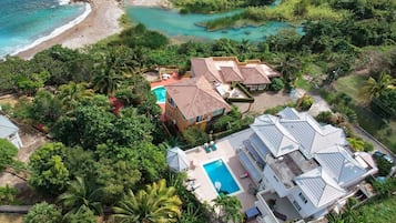 Vue aérienne d’un complexe hôtelier doté d’une piscine, d’un accès à la plage et d’une végétation luxuriante.