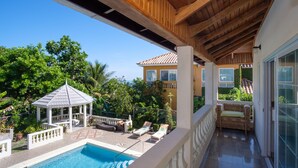 A pool area with lounge chairs, a gazebo, and a covered patio with a view of a house and greenery. - Luxurious 7-bedroom villa with spectacular sea view and private pool (Tower Isle)