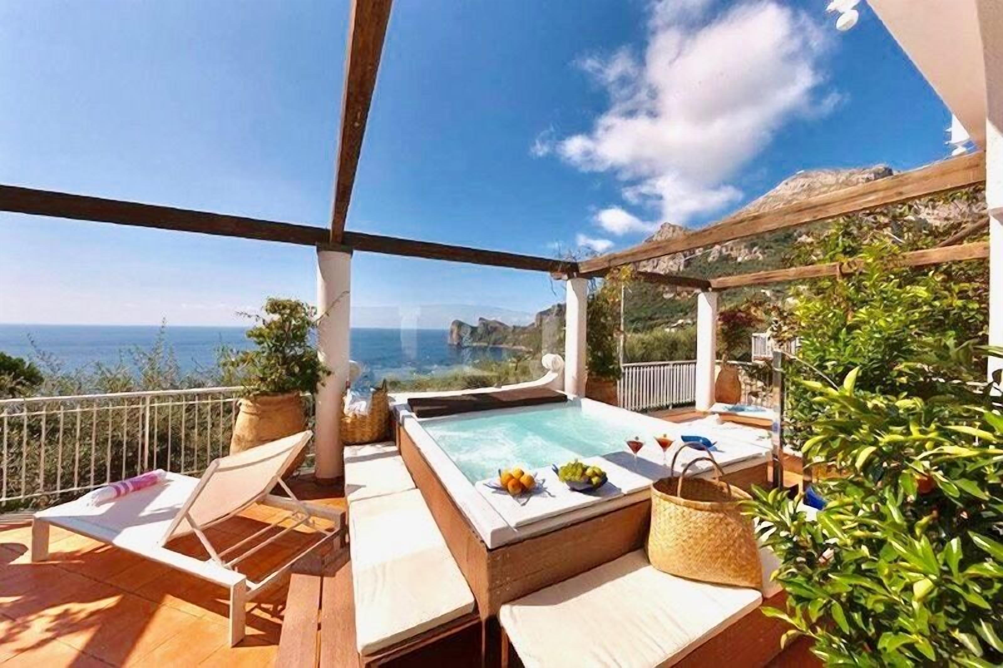 Una terrazza sul tetto con idromassaggio, poltrona relax e vista mare.