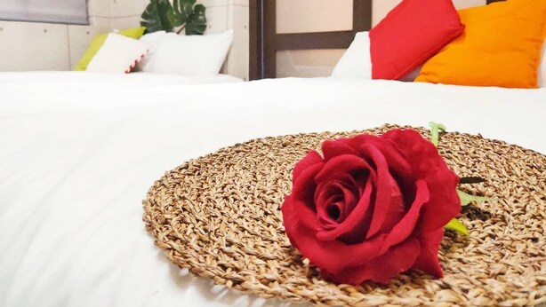 A neatly made bed with a woven placemat and a single red rose. - Freestyle A Sun Yat-san Memorial Hall (Taipei)