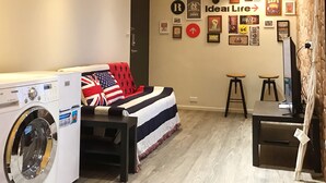 A laundry room with a washing machine, a bed with an American flag blanket, and a wall with various framed items and a sign that says "Ideal Life". - Freestyle A Sun Yat-san Memorial Hall (Taipei)