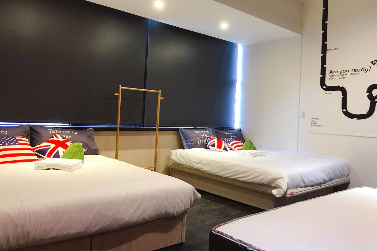 A hotel room with two beds, a wooden ladder, and a wall with motivational quotes.