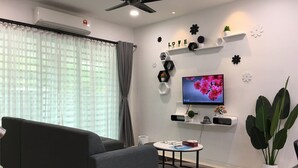 A modern living room with a grey sofa, a round coffee table, a flat-screen TV, and decorative wall shelves. - Ipoh Paradise Homestay Station 18 (Ipoh)