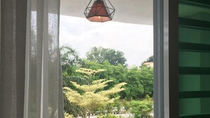 A view from a balcony with a hanging pendant light, a green railing, and a glimpse of trees and greenery outside. - Ipoh Paradise Homestay Station 18 (Ipoh)