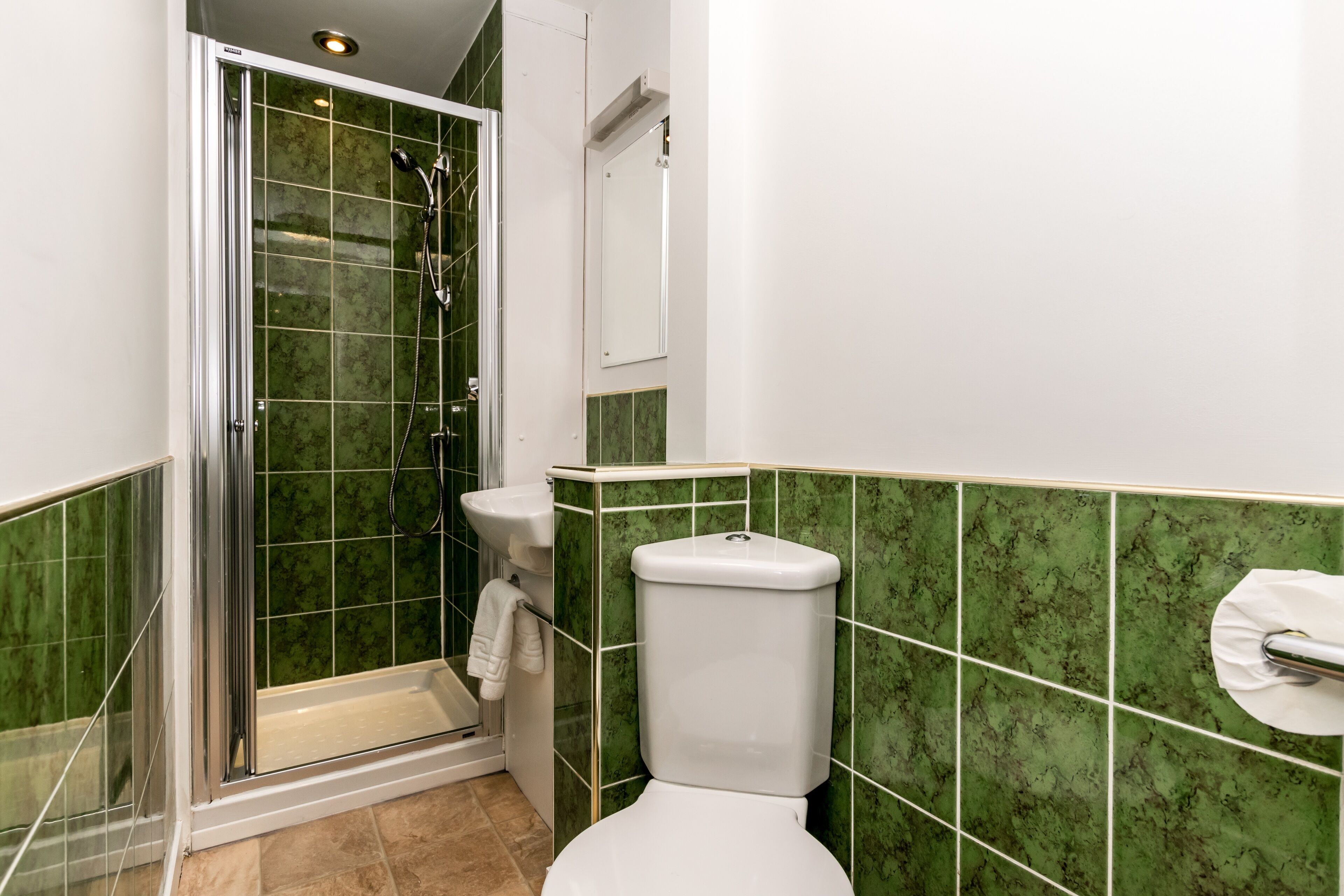 Un baño con ducha envuelta en vidrio, inodoro y lavamanos.