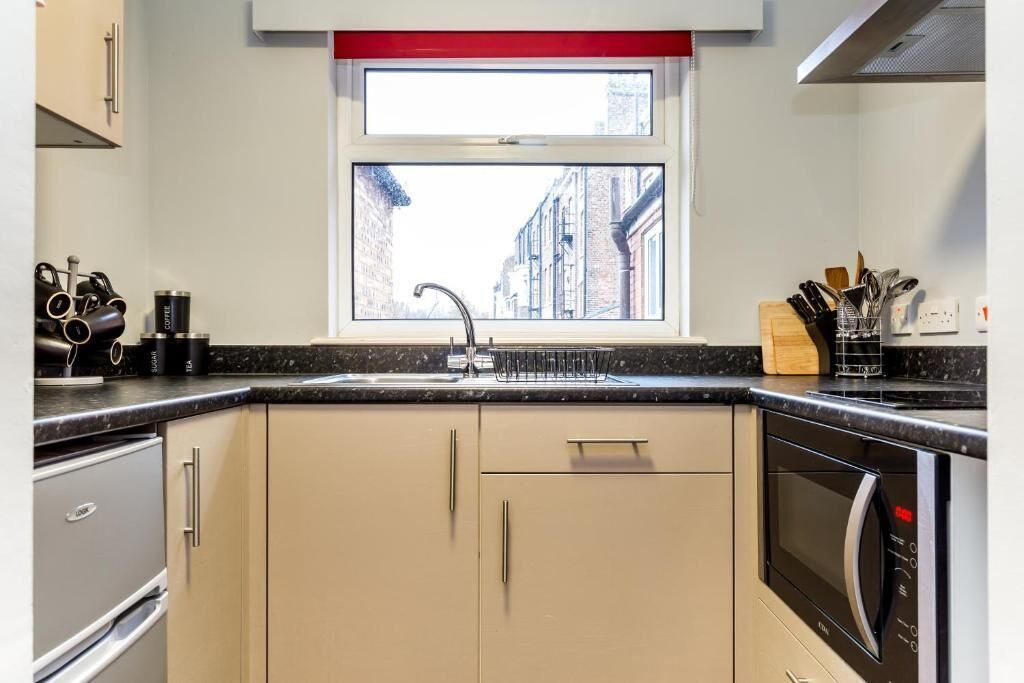 A modern kitchen with a window, stainless steel appliances, and a black countertop.