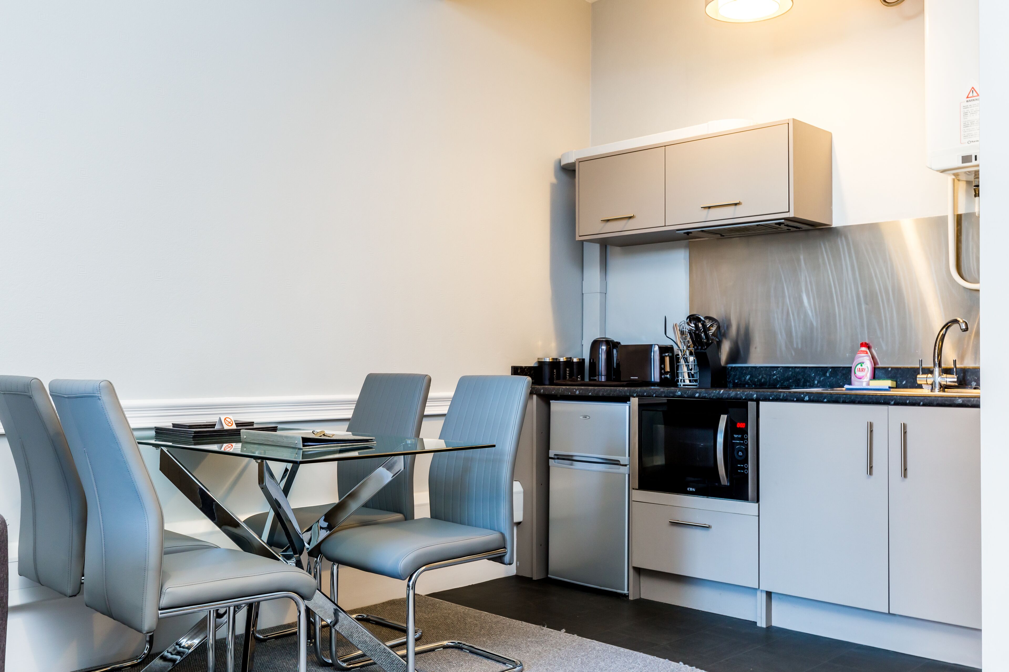 Una cocina compacta con comedor, que incluye una mesa con sillas, un refrigerador, un horno y un microondas.
