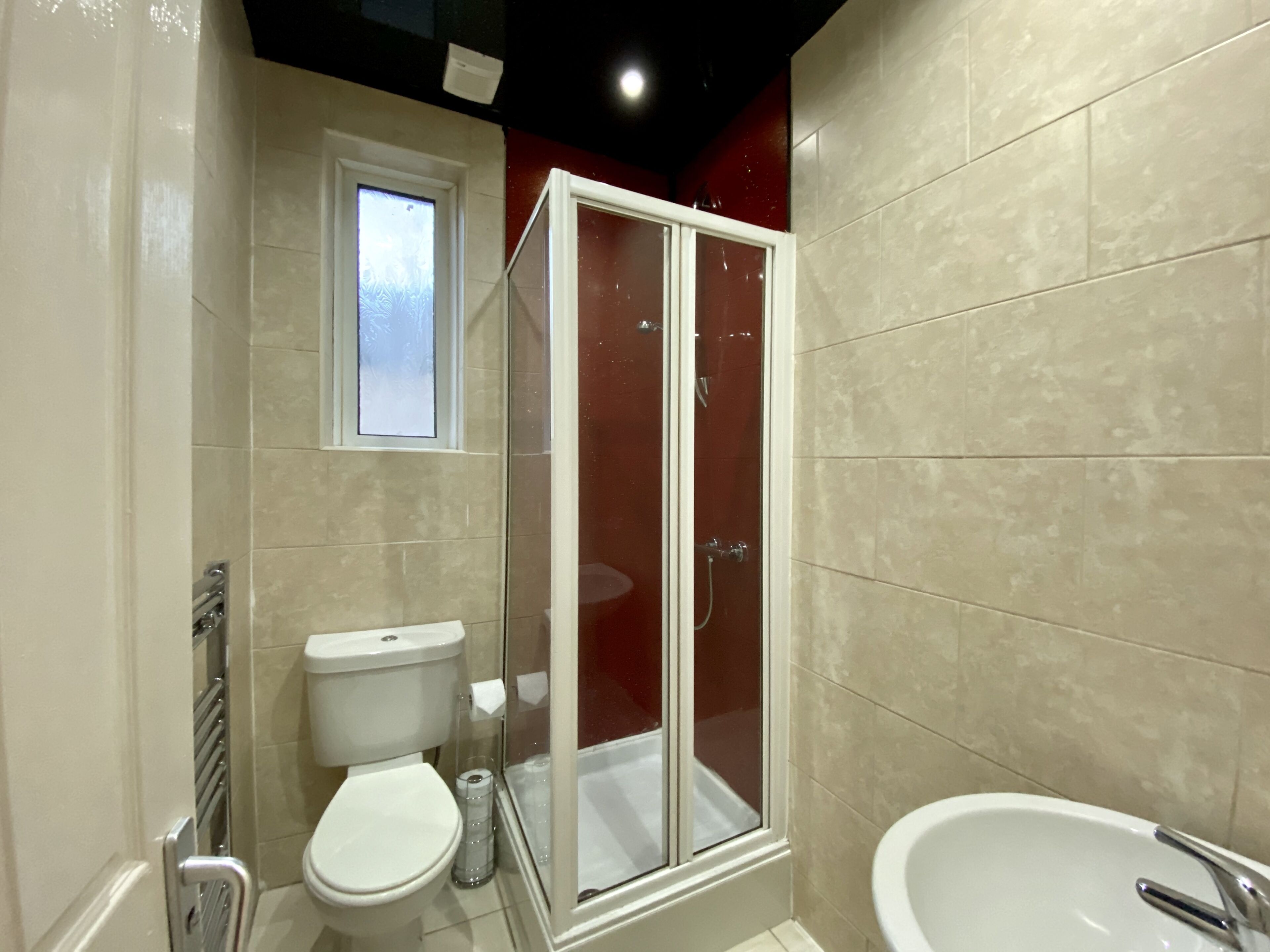 A bathroom with a toilet, a glass-enclosed shower, and a sink.