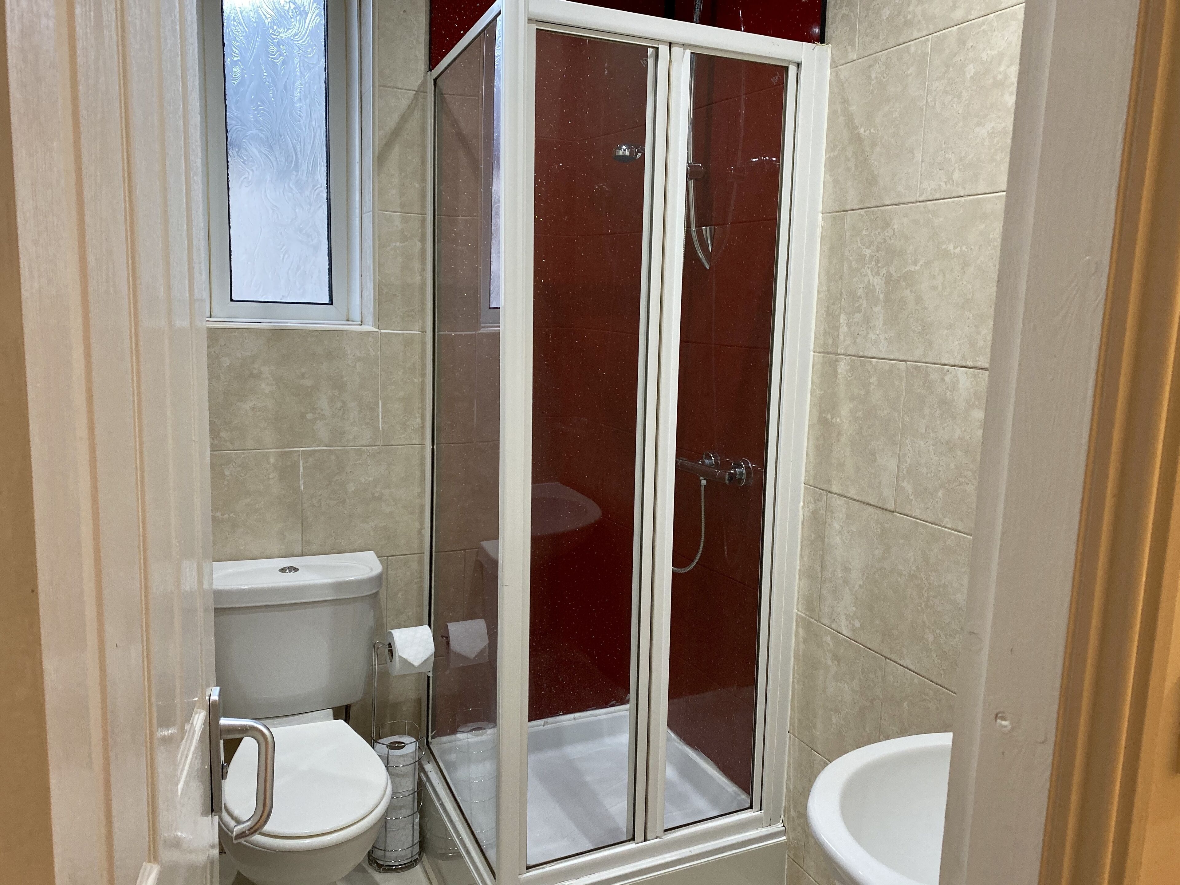 Un baño con ducha acristalada, inodoro y lavamanos.