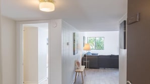 A modern interior with a wooden floor, a sofa, a lamp, and a door with a keypad lock. - 2077 Beachwood (Fernandina Beach)