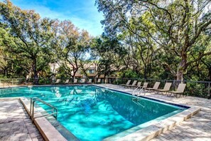 A rectangular swimming pool with clear blue water, surrounded by a brick deck and shaded by trees. - 2077 Beachwood (Fernandina Beach)
