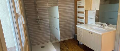 A bathroom with a shower, sink, and vanity.