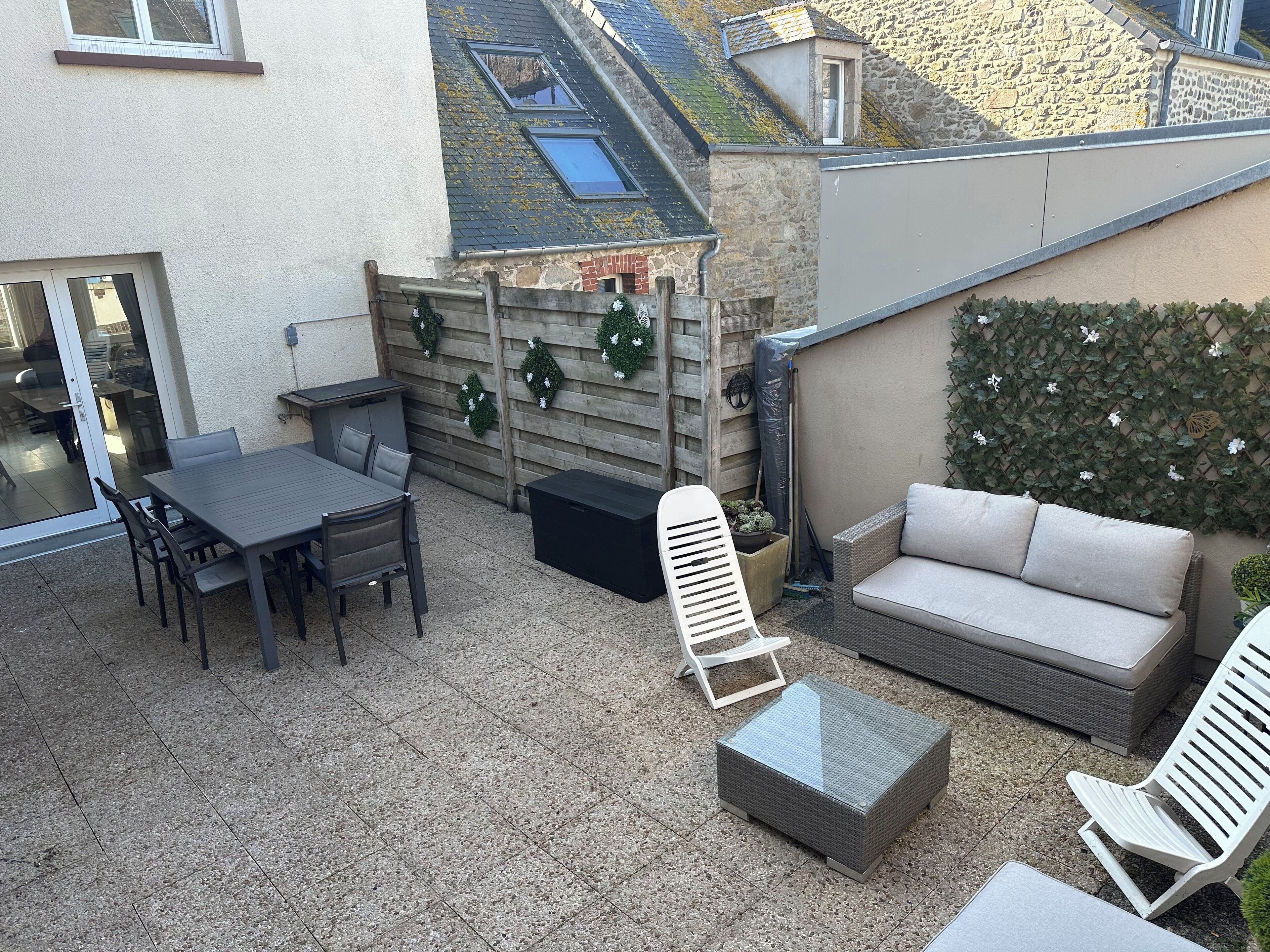 Un patio con mesa y sillas, un sofá y una pequeña silla blanca.