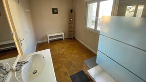 Un baño con lavamanos blanco, espejo y ventana con vistas al exterior.