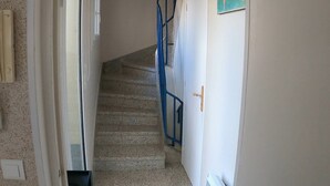 Una escalera con barandilla azul que lleva a una puerta.