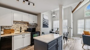 A modern kitchen with white cabinets, a large island, and a dining area with a table and chairs.