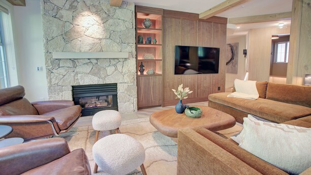 A modern living room with leather sofas, a stone fireplace, a flat-screen TV, and a wooden entertainment unit. - Designer 4BR, 3 Bath Townhouse w Mtn Views, Hot Tub, Parking for 2 vehicles (Whistler)
