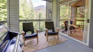 A balcony with two chairs and a piano, overlooking a forested area. - Designer 4BR, 3 Bath Townhouse w Mtn Views, Hot Tub, Parking for 2 vehicles (Whistler)