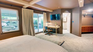 A hotel room with two beds, a desk, a chair, a TV, and a bathroom visible through an open door. - Designer 4BR, 3 Bath Townhouse w Mtn Views, Hot Tub, Parking for 2 vehicles (Whistler)