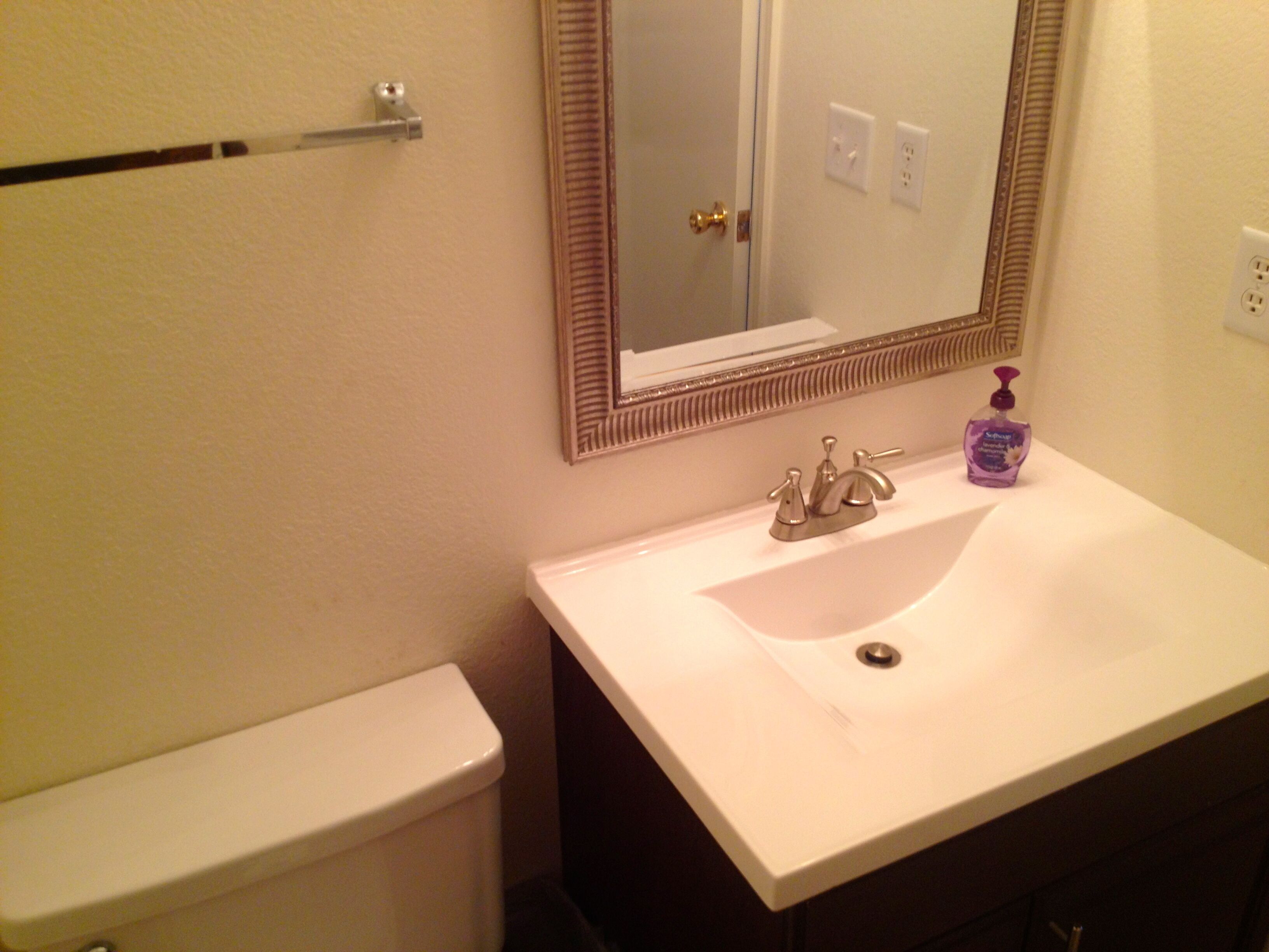 A bathroom with a white sink, a mirror, and a toilet.