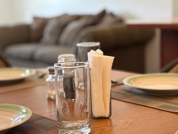 A dining table set with clear glasses, a folded napkin, and salt and pepper shakers.