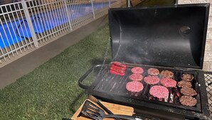 Una parrilla con varias hamburguesas asándose.