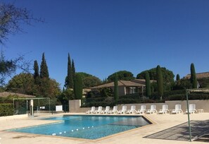 Ein Pool mit Liegestühlen, umgeben von Bäumen und Gebäuden.