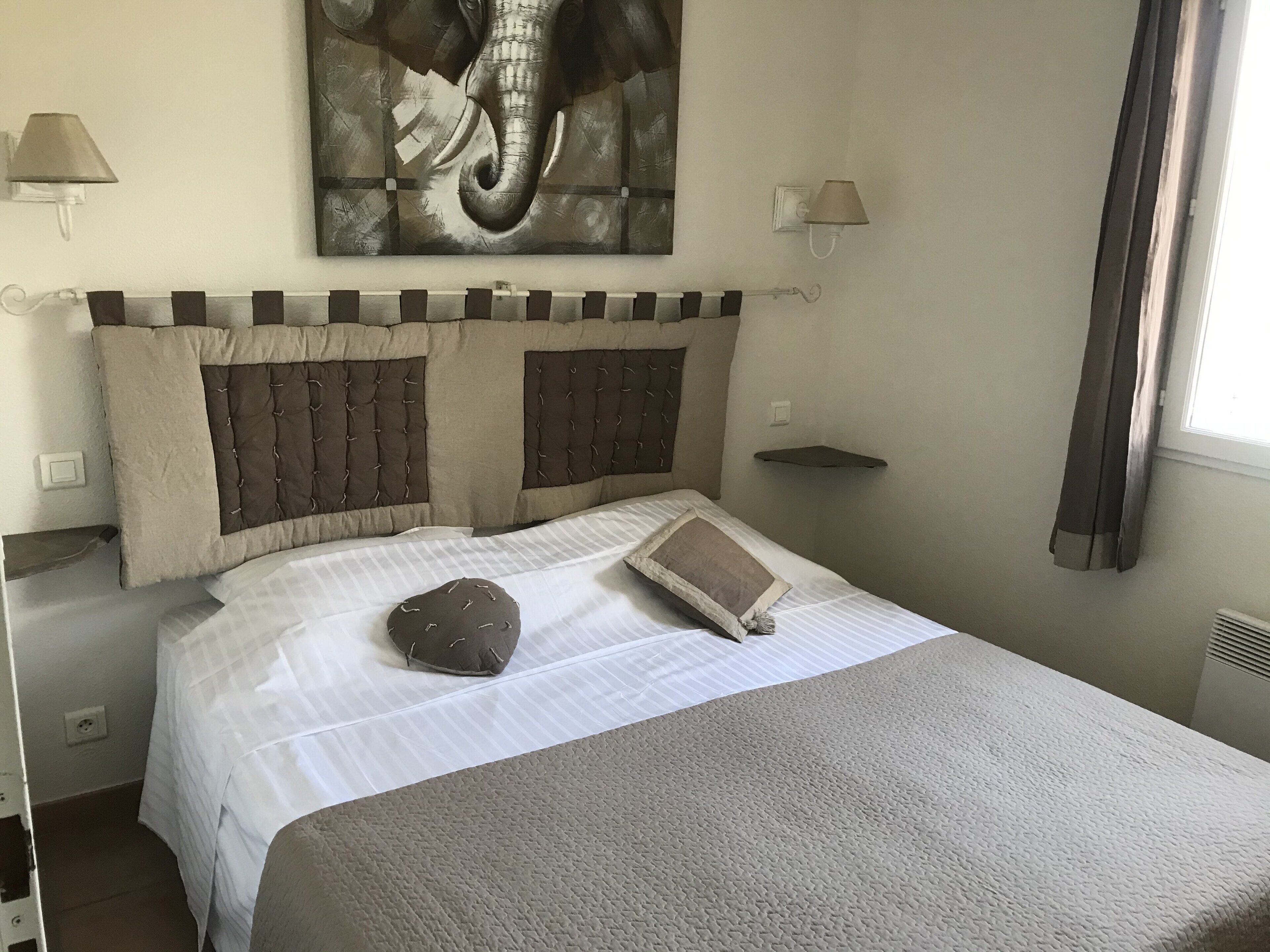 A neatly made bed with a headboard, a decorative pillow, and a book on the bed.