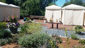 A garden area with two white tents, a wooden bench, and various potted plants. - Walk to Beach Central AC WiFi Beach Pearl (Chatham)