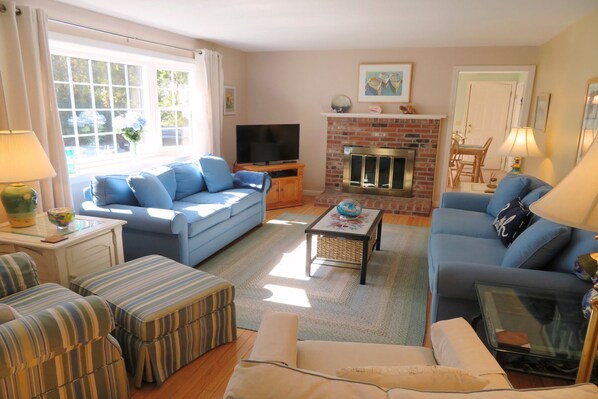 A living room with a blue sofa, striped ottoman, and a fireplace. - Walk to Beach Central AC WiFi Beach Pearl (Chatham)