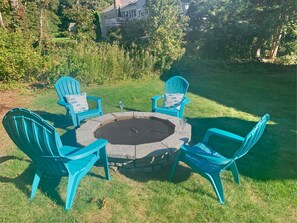A circular stone fire pit surrounded by four turquoise chairs with cushions, set on a grassy lawn. - Walk to Beach Central AC WiFi Beach Pearl (Chatham)