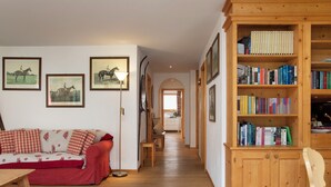 A cozy living room with a red and white checkered sofa, a wooden bookshelf filled with books, and framed pictures on the wall.