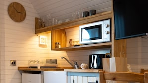 Une cuisine compacte avec des meubles de rangement en bois, un four à micro-ondes, un réfrigérateur et une table à manger en bois.