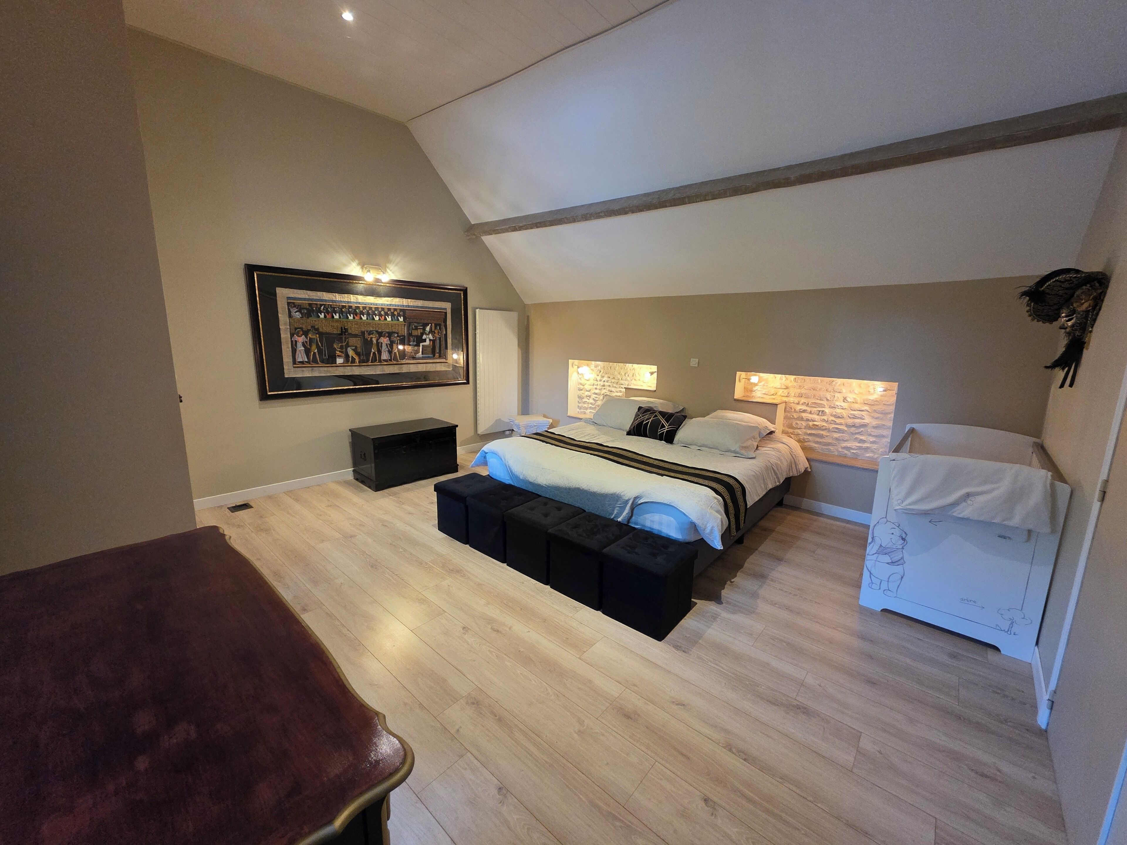 A bedroom with a bed, bedside tables, a desk, a chair, and a framed picture on the wall.
