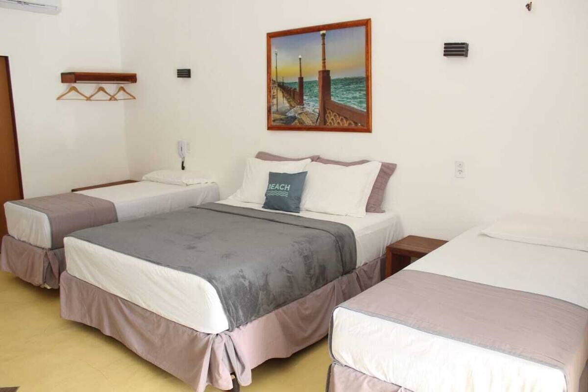 Ein Hotelzimmer mit zwei Betten, einem Bild eines Piers und einem kleinen Tisch mit einer Lampe.