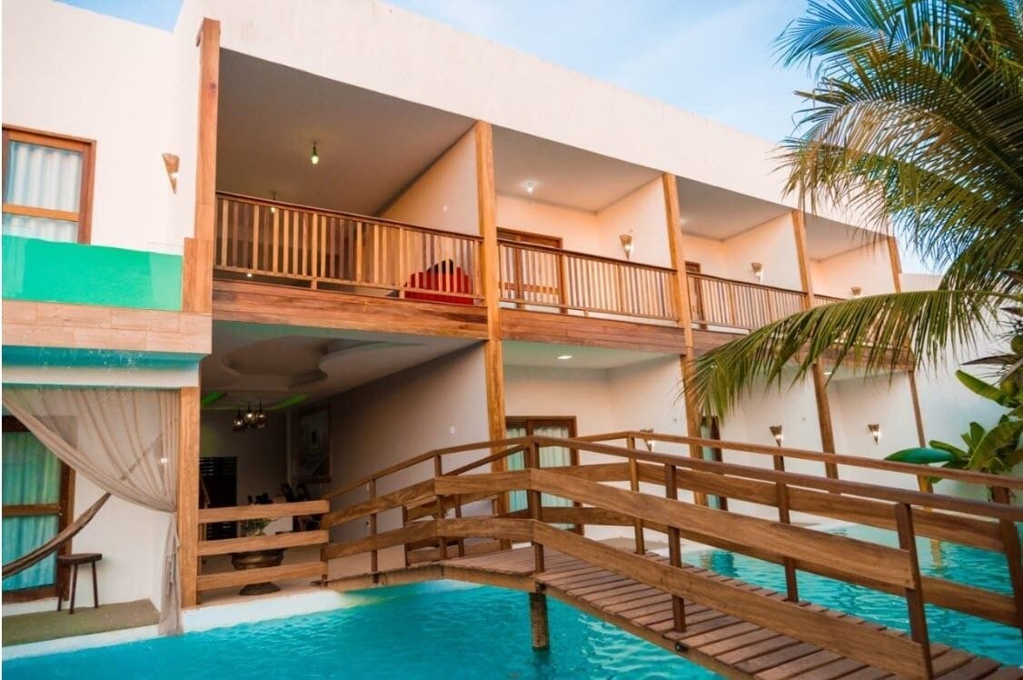 A two-story building with a pool, wooden deck, and a balcony.