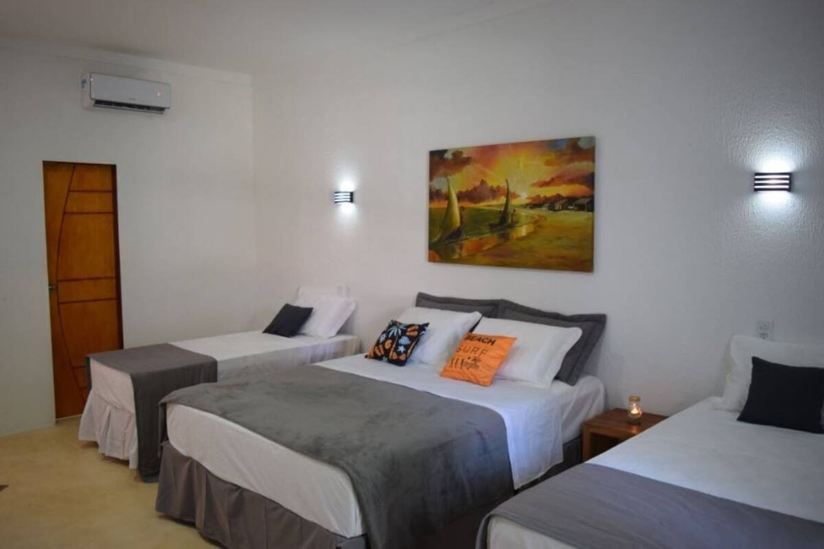 Ein Hotelzimmer mit zwei Einzelbetten, einem Bild an der Wand und einer Klimaanlage.